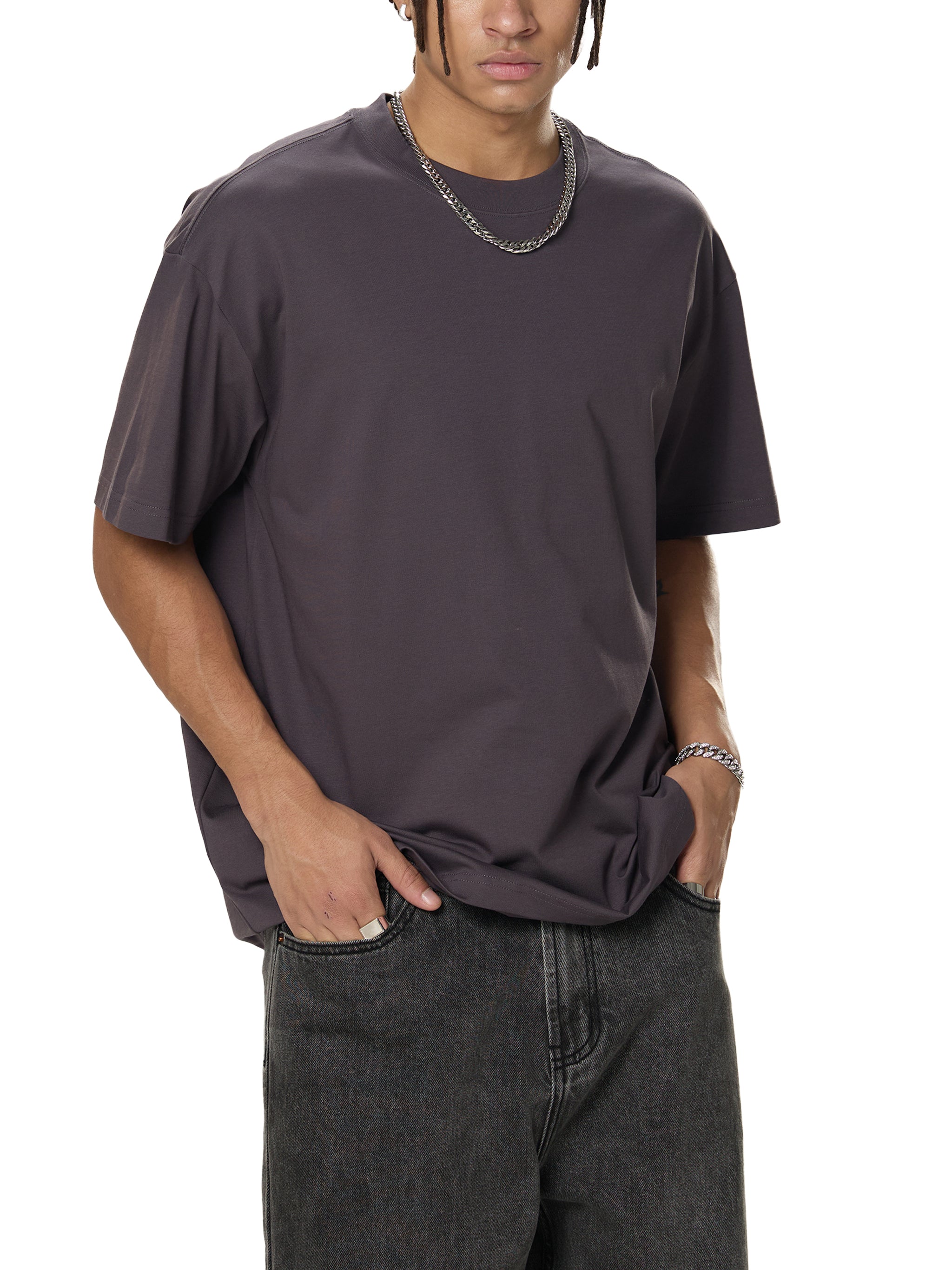 Man wearing oversized dark grey t-shirt and jeans in modern streetwear style
