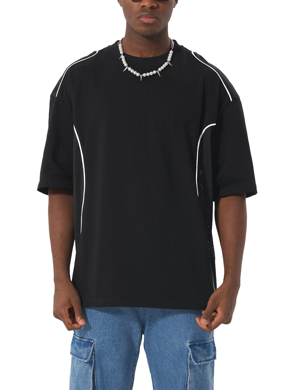 Man wearing black oversized streetwear t-shirt with white piping and cargo jeans