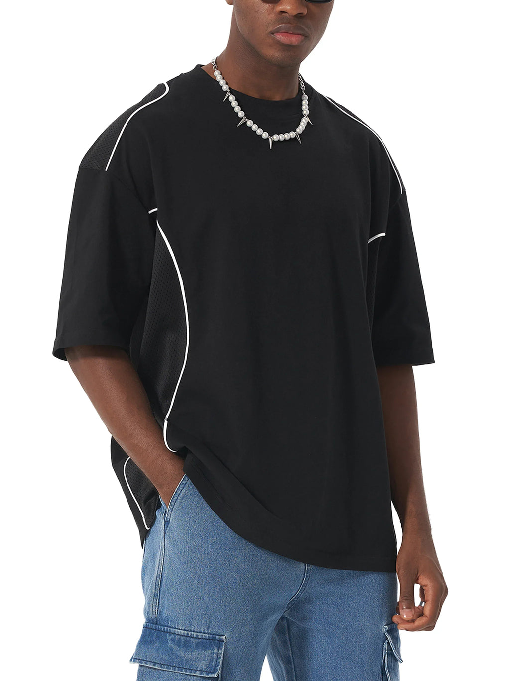 Man wearing oversized black streetwear t-shirt with white piping and blue cargo jeans
