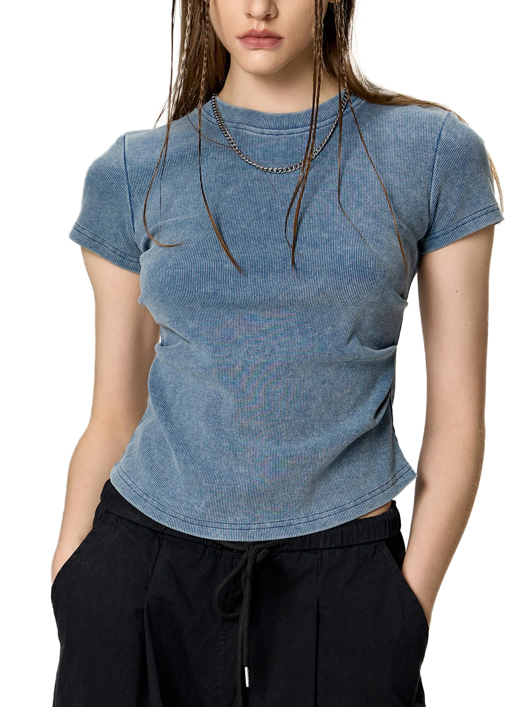 Woman wearing a fitted blue ribbed t-shirt and black drawstring pants, urban streetwear style