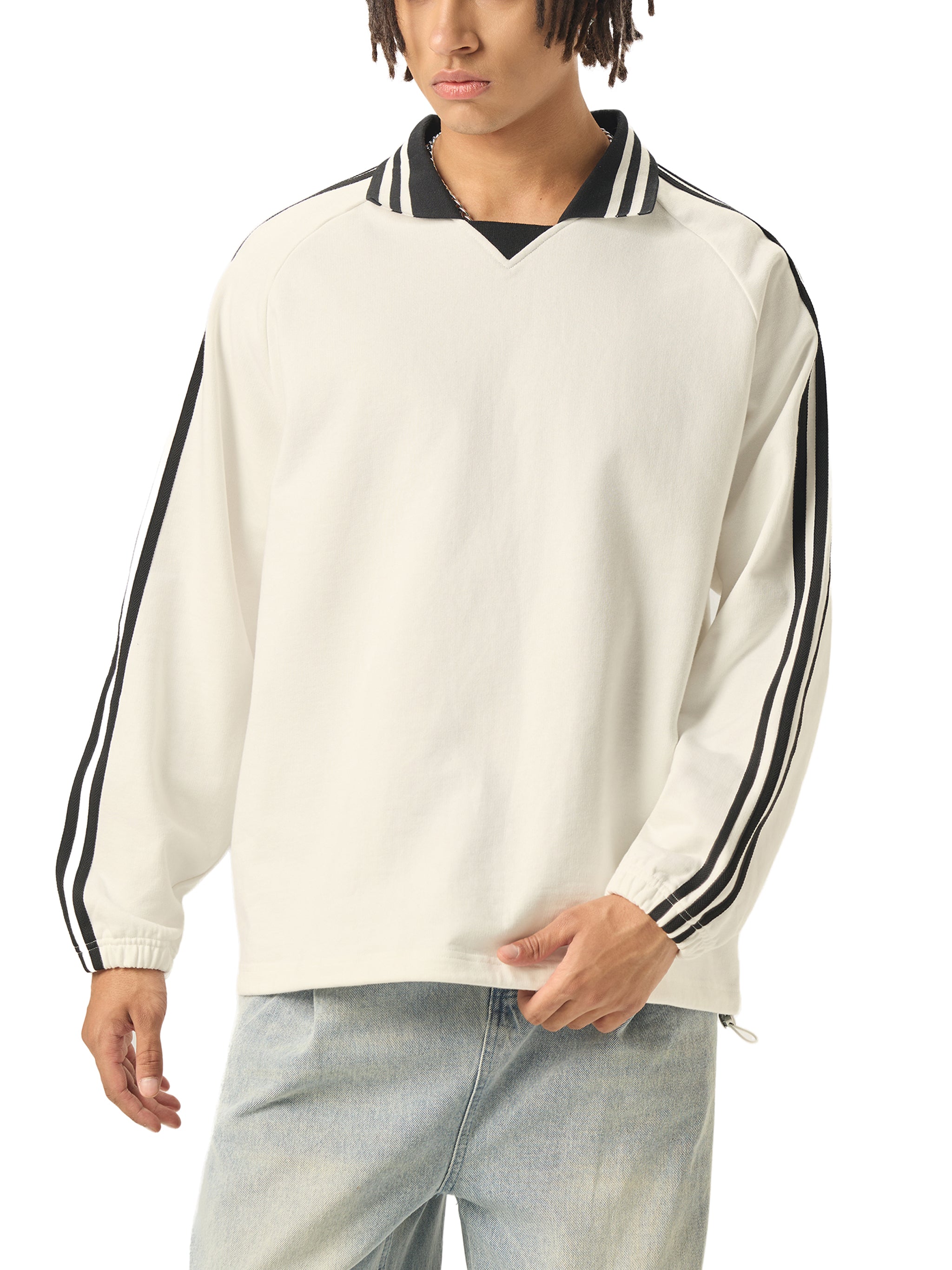 Man wearing an oversized white long sleeve shirt with black stripes on sleeves and collar