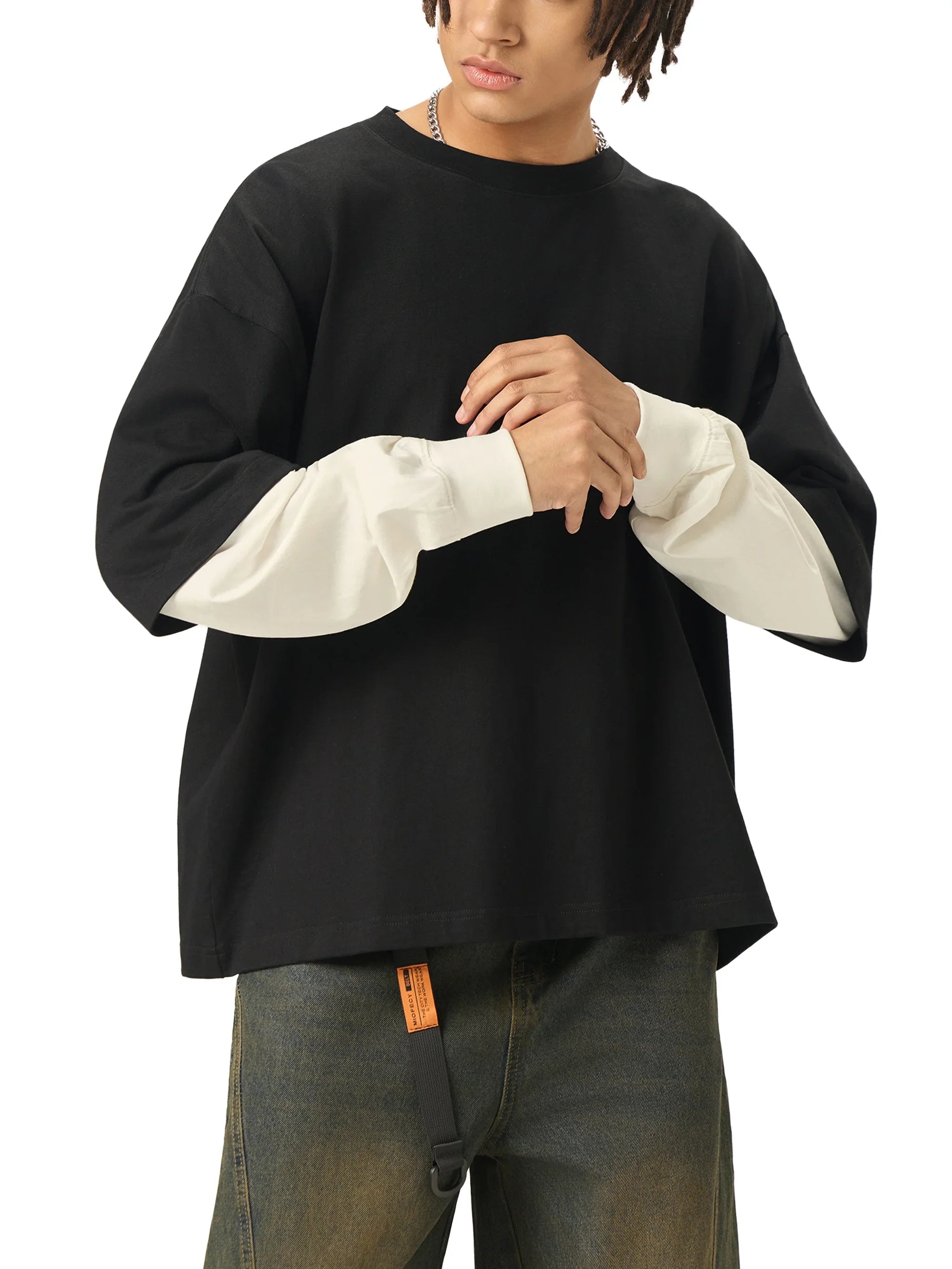 Man wearing black oversized streetwear t-shirt with white layered long sleeves and jeans
