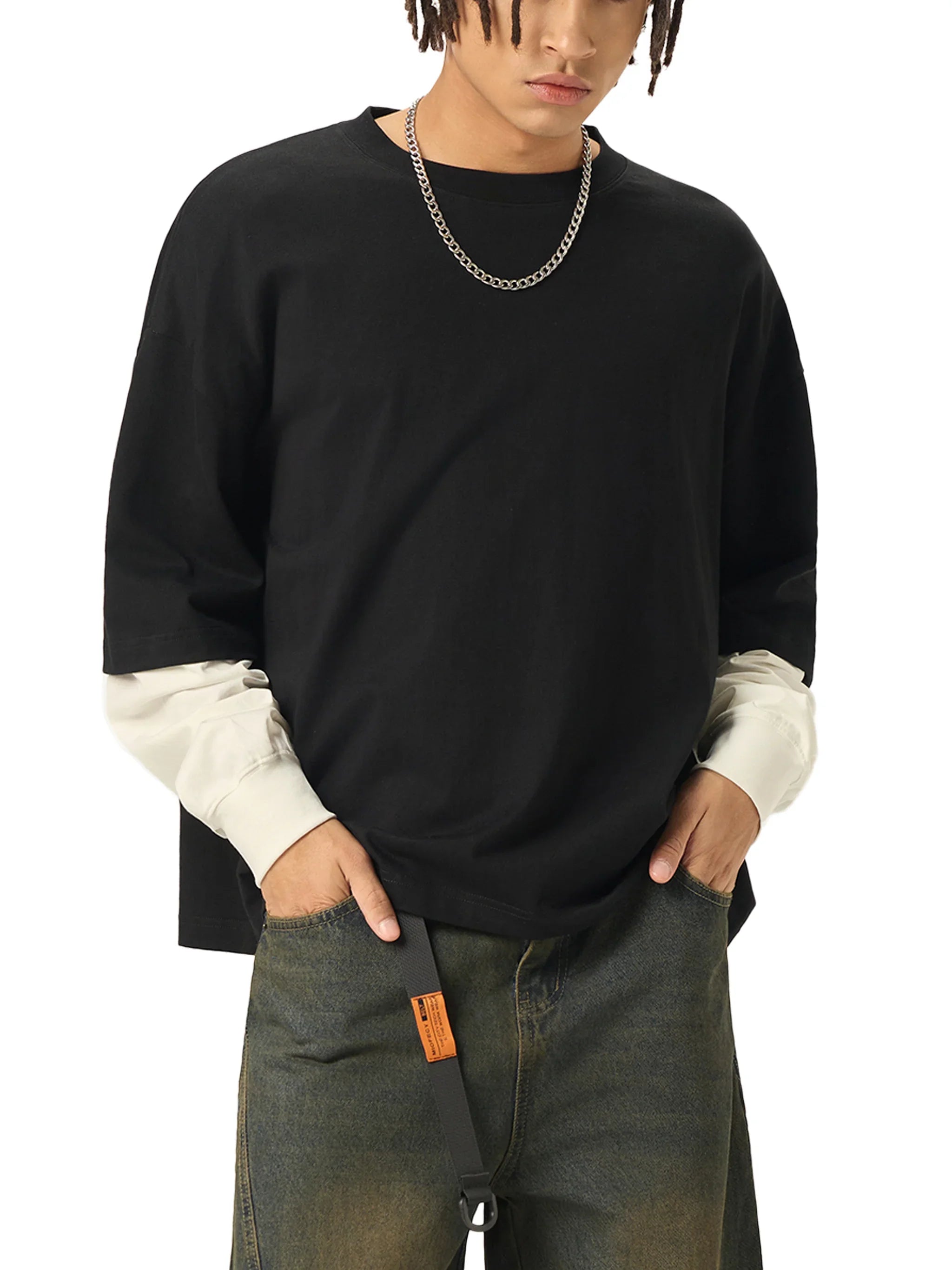 Man in oversized black t-shirt with chain necklace, layered sleeves, and streetwear jeans