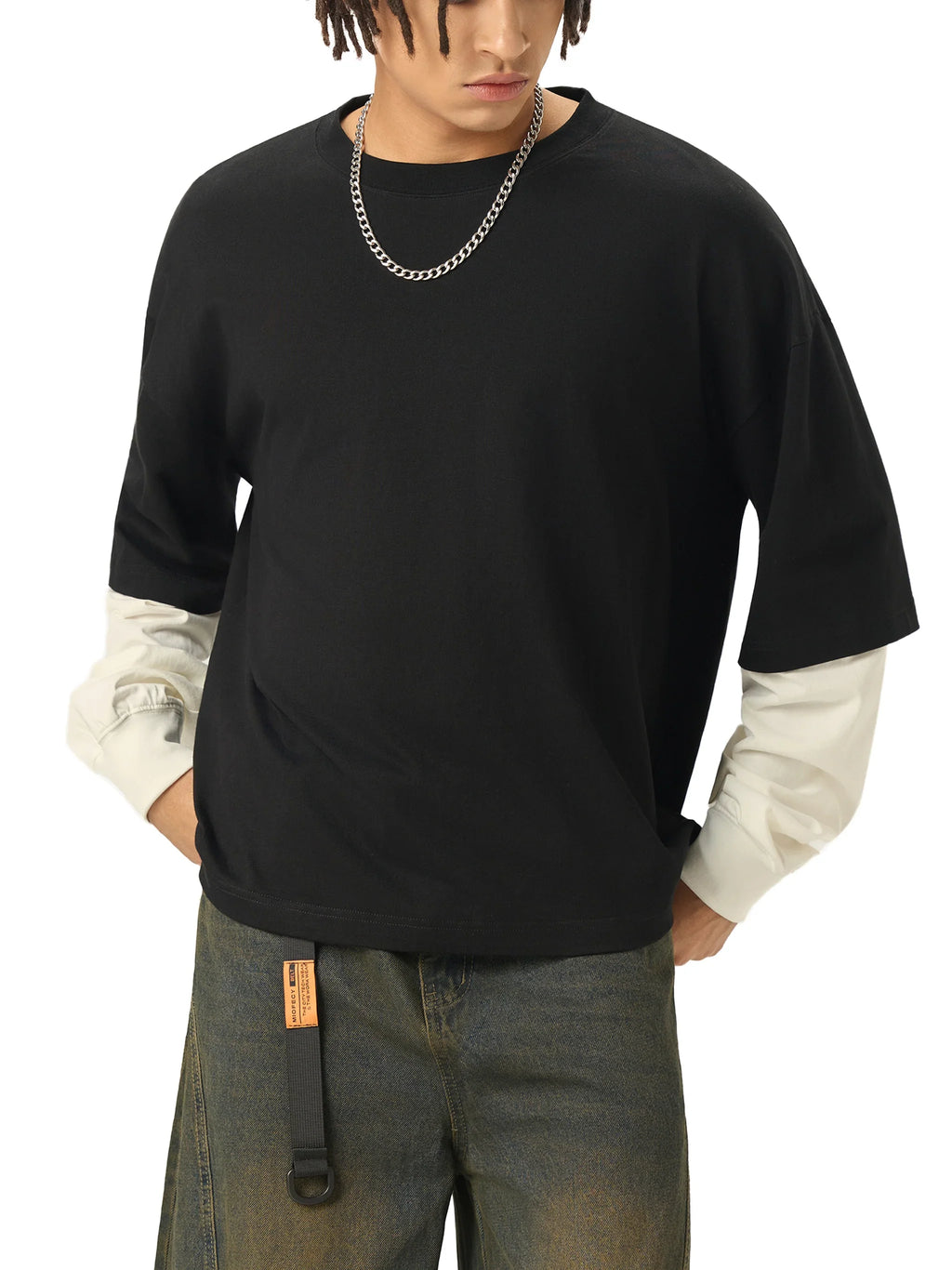 Man wearing oversized black streetwear t-shirt layered over white sleeves with jeans