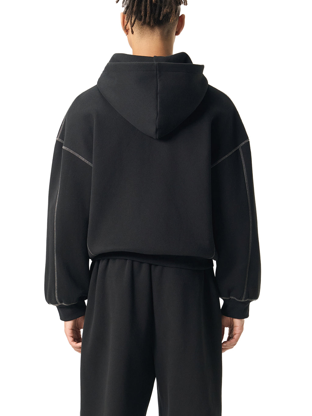 Back view of a person wearing an oversized black hoodie and matching black pants
