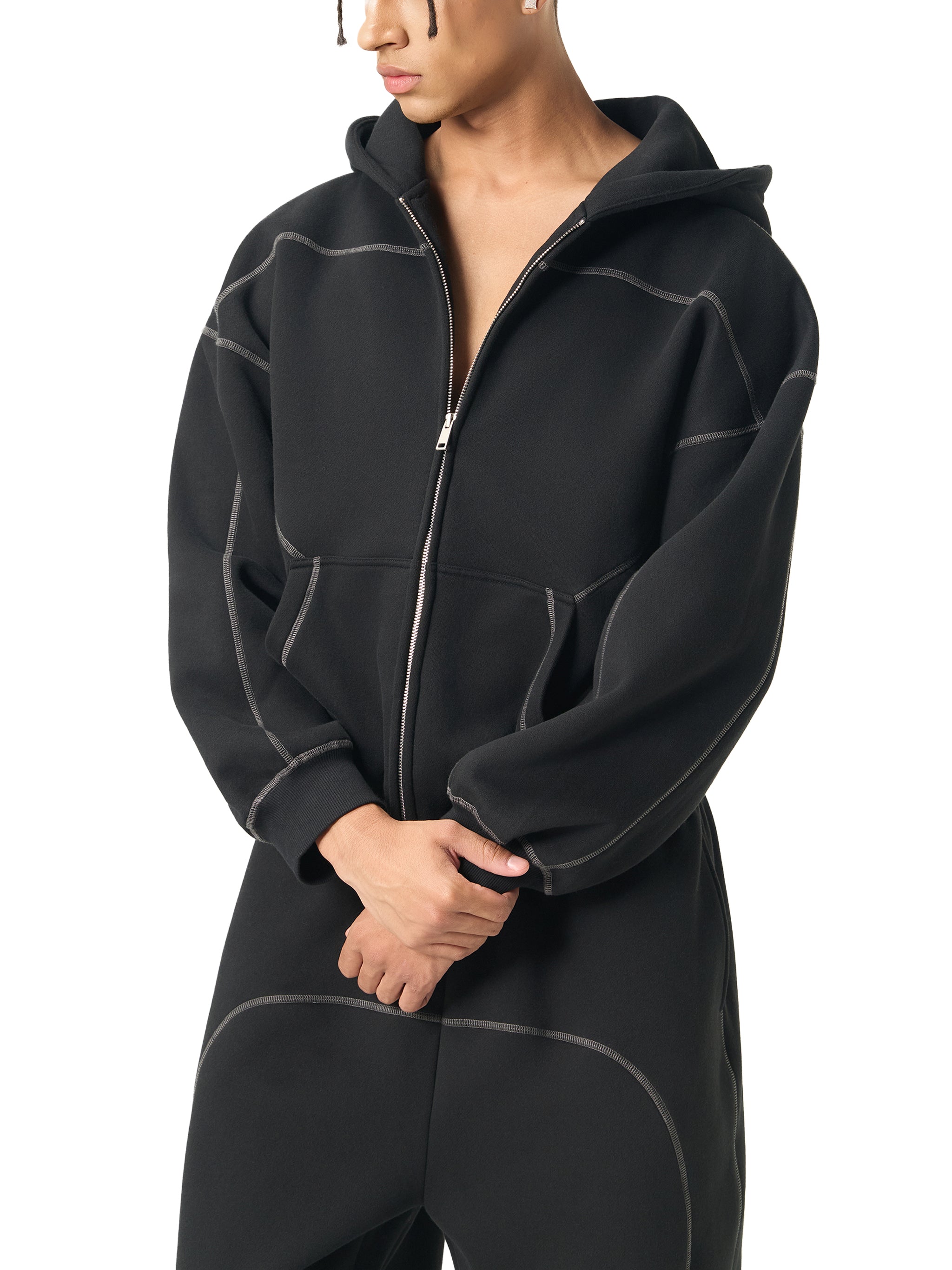 Man wearing oversized black zip-up hoodie with contrast stitching, modern streetwear style