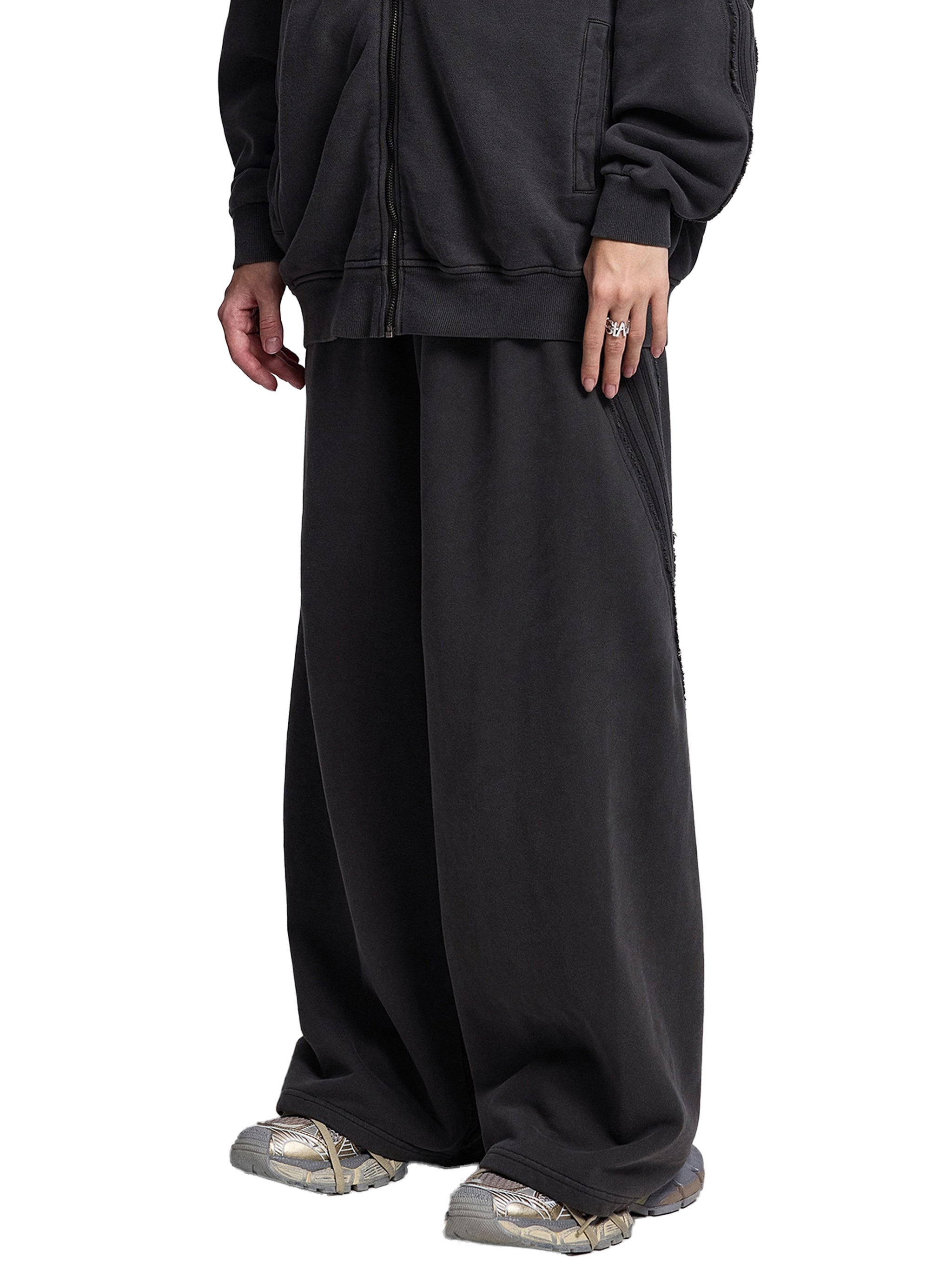Oversized black wide-leg streetwear pants paired with chunky sneakers, urban style
