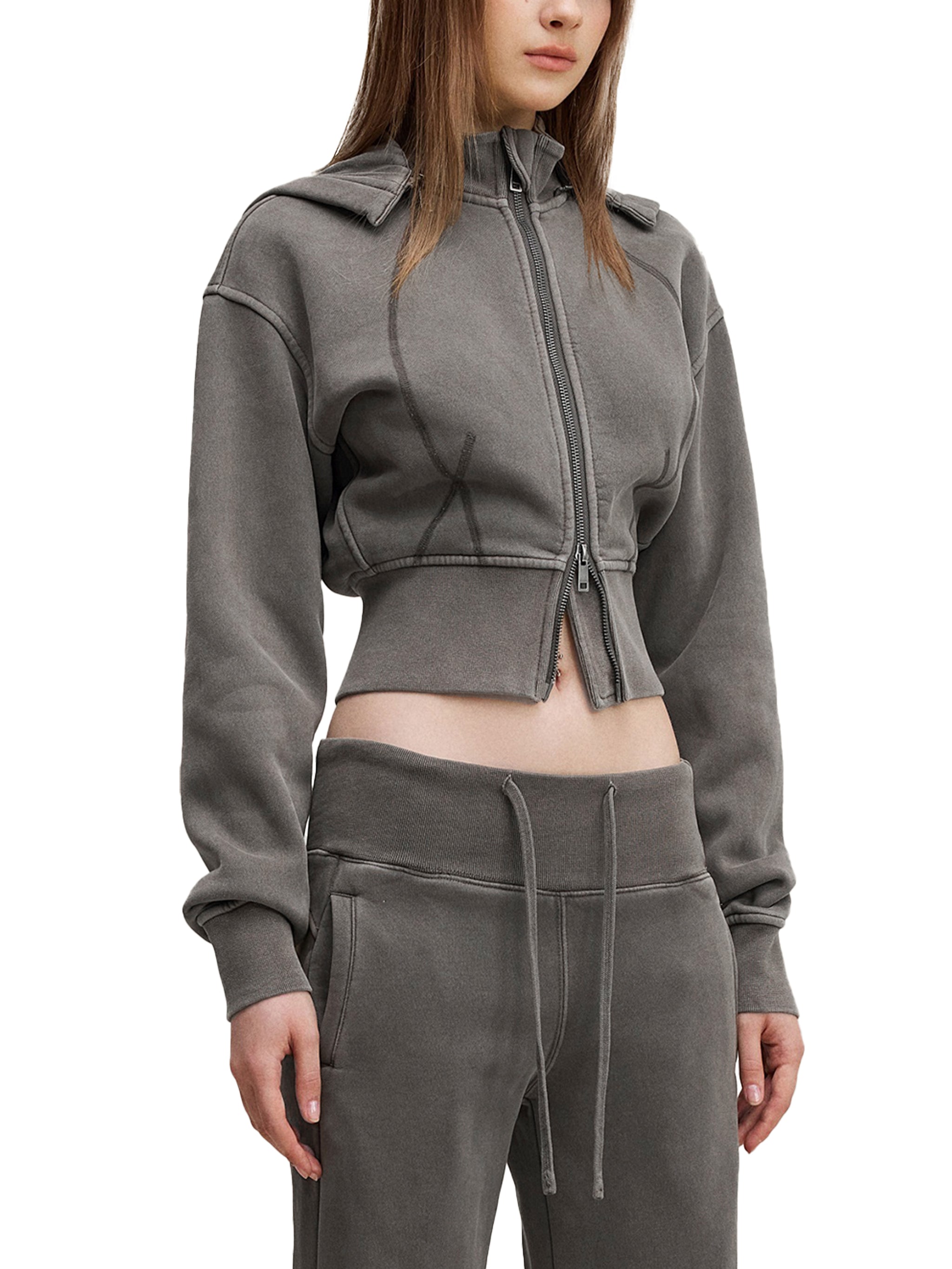 Woman wearing a grey cropped zip-up hoodie and matching drawstring sweatpants, streetwear style