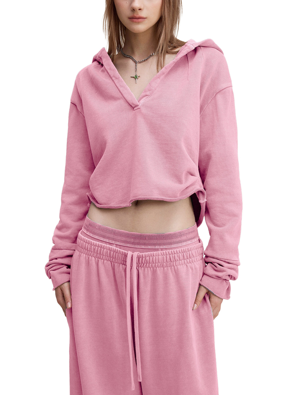 Woman wearing oversized pink cropped hoodie and matching pink sweatpants, modern streetwear style