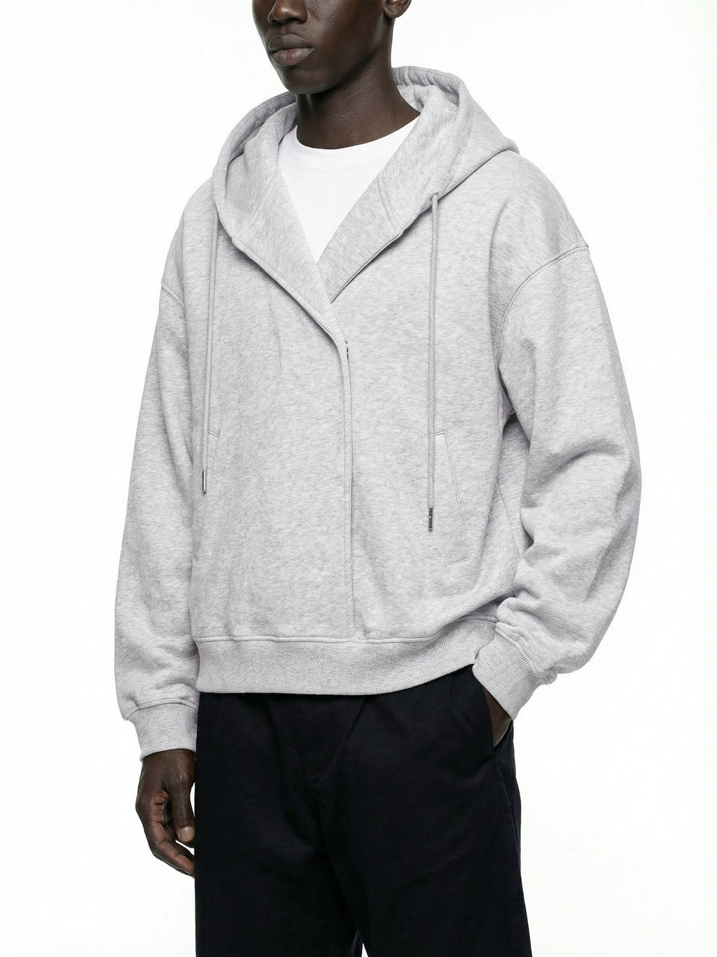 Man wearing an oversized light grey hoodie with drawstrings and black pants