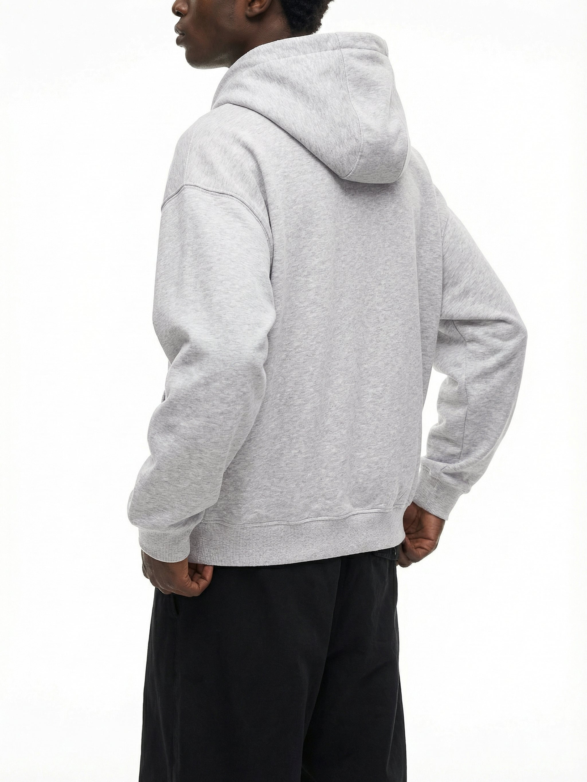 Back view of man wearing light grey oversized hoodie and black pants, streetwear style